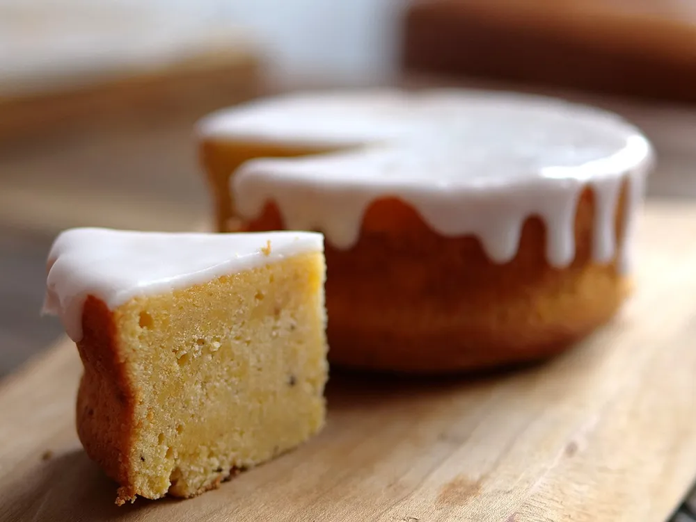 木の板に乗ったカットしたレモンケーキとホールのレモンケーキの画像