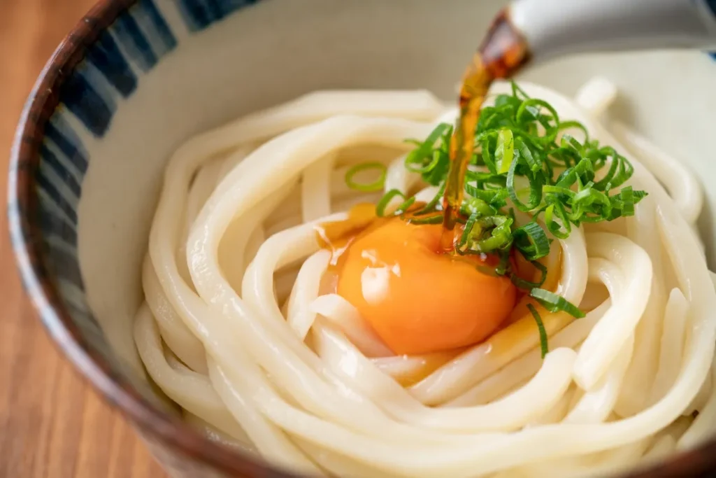 釜玉讃岐うどんにつゆがかけられている画像