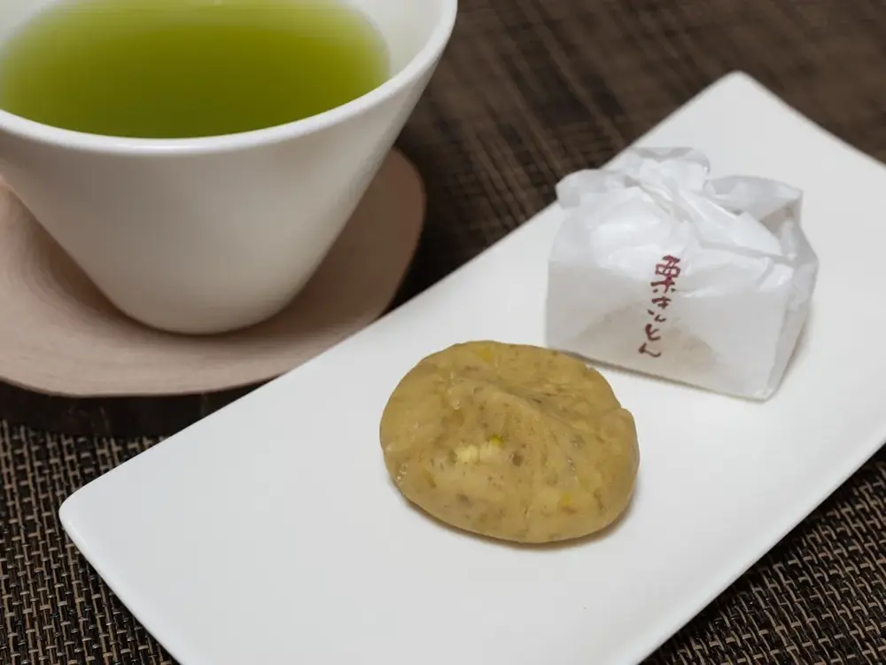 皿に盛られた岐阜県の栗きんとんと呼ばれるシンプルな栗のお菓子とお茶の画像