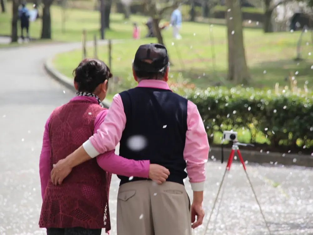 仲良く写真を撮る老夫婦の後ろ姿の画像
