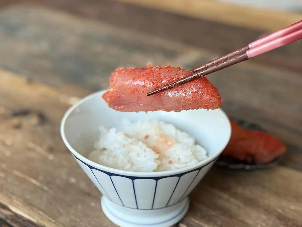 かねふくの明太子をご飯の上にのせてお箸で持ち上げた画像