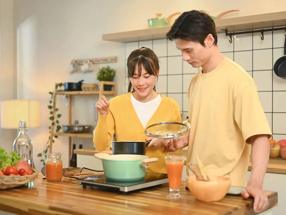 キッチンで料理を作る夫婦の画像