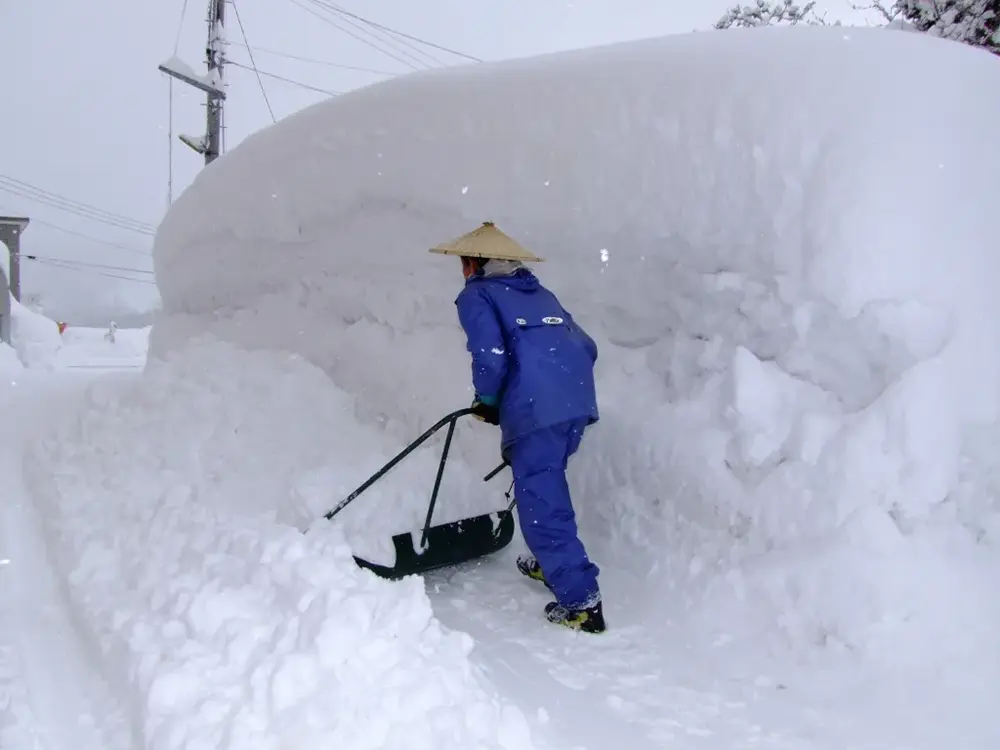 降り積もった雪をスノーダンプで除雪をする住民の画像