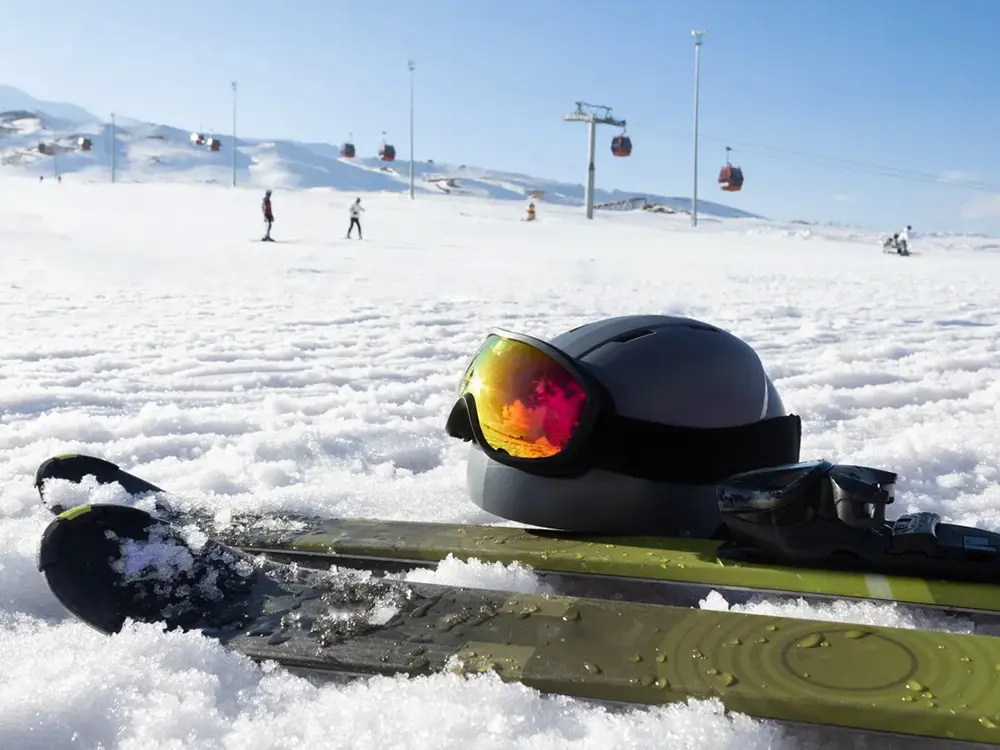 冬のスキー場に置かれたヘルメットとスキー板の画像