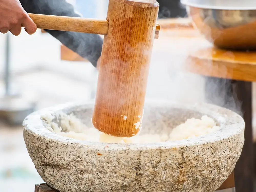 臼と杵での餅つきの様子の画像