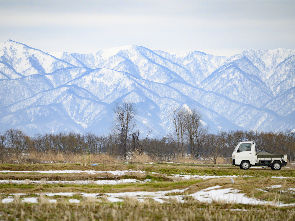 冬の田園風景の中を走るトラックの画像