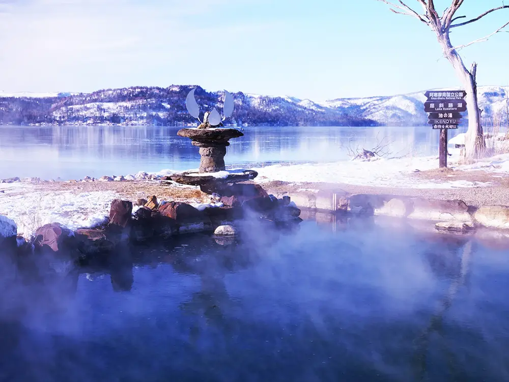 雪景色の中にある湖畔の野外温泉の画像