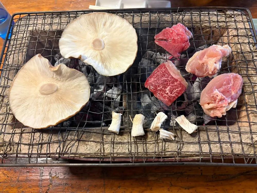 網の上に並べたしいたけと肉の画像