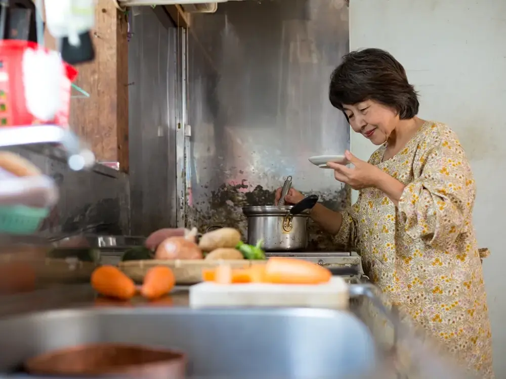 台所で料理を作っている母親の画像）
