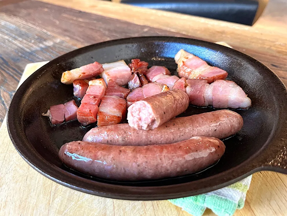 焼きあがったベーコンと半分に切ったソーセージの断面が見える画像