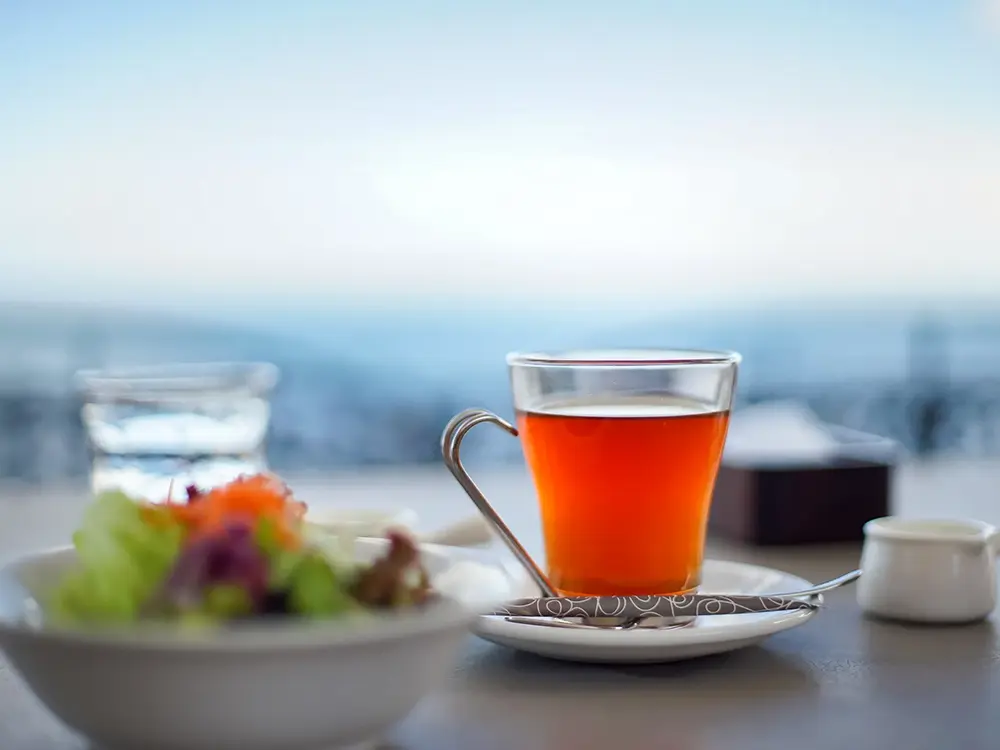 海辺のカフェのテーブルに乗ったお茶とサラダのイメージ画像