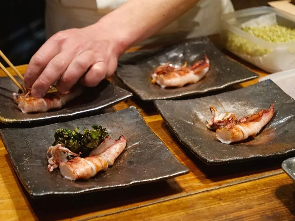 ささ烏賊の焼き物を皿に盛りつけている様子の写真