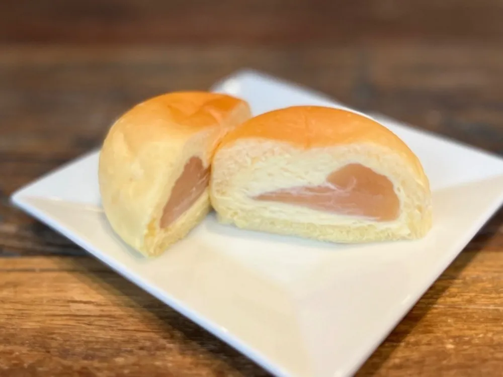 八天堂くりーむパン桃味を半分に切ってお皿に載せた画像)