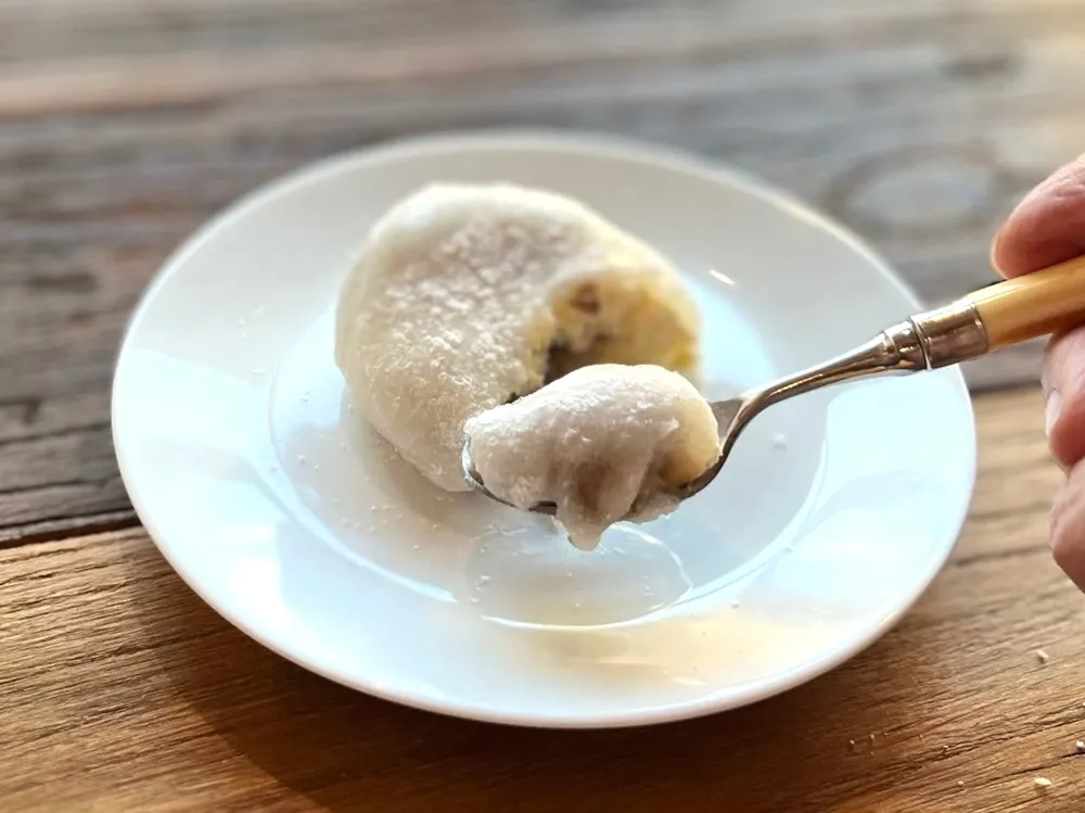 お皿に載せた八天堂とろけるくりーむ大福をスプーンですくっている画像