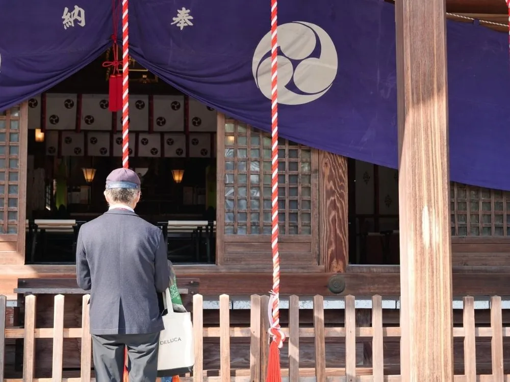 唐津神社の本殿前で手を合わせるマロンの写真