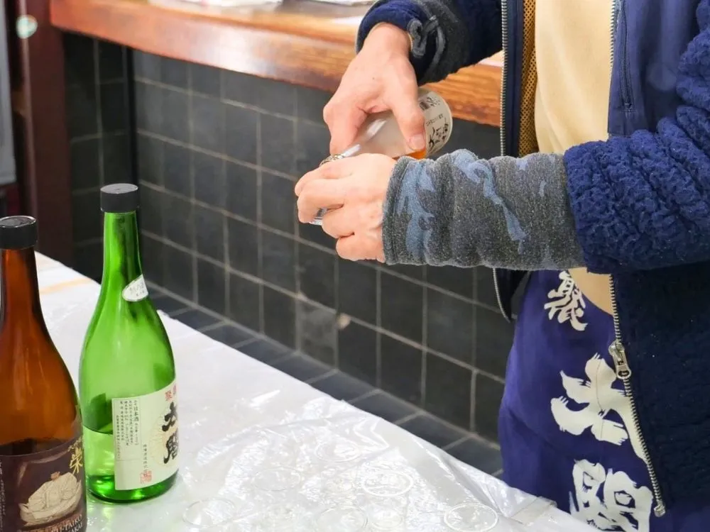 地酒販売処「太閤」の店主が試飲用の酒を注ぐ様子の画像