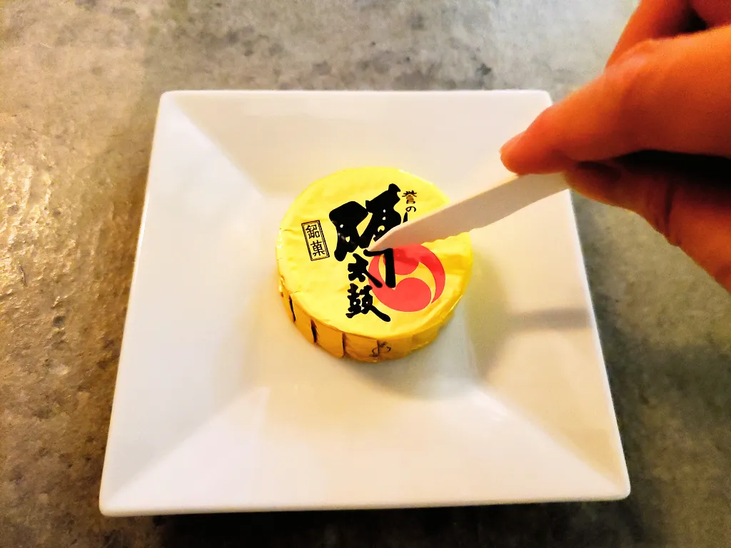 白い皿にのせた誉の陣太鼓1つを紙ナイフで切る画像