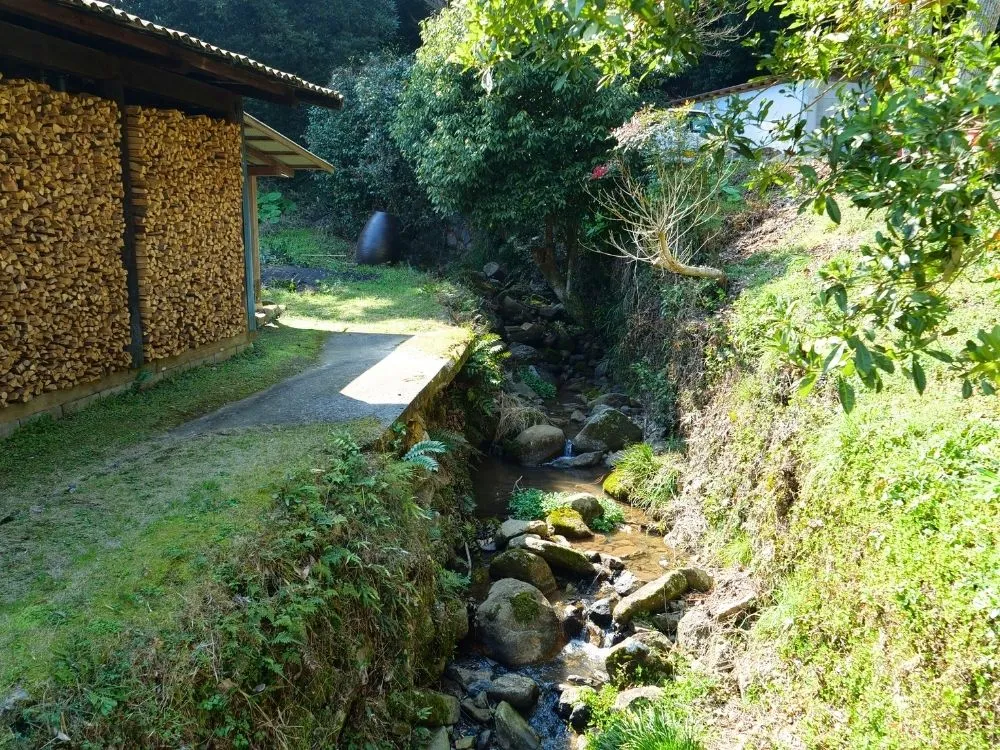 登窯・横に積まれた薪と小川の風景の画像
