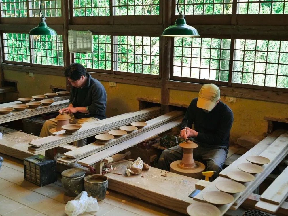 ろくろ場で器と向き合う中里健太さんと中里太亀さんの写真