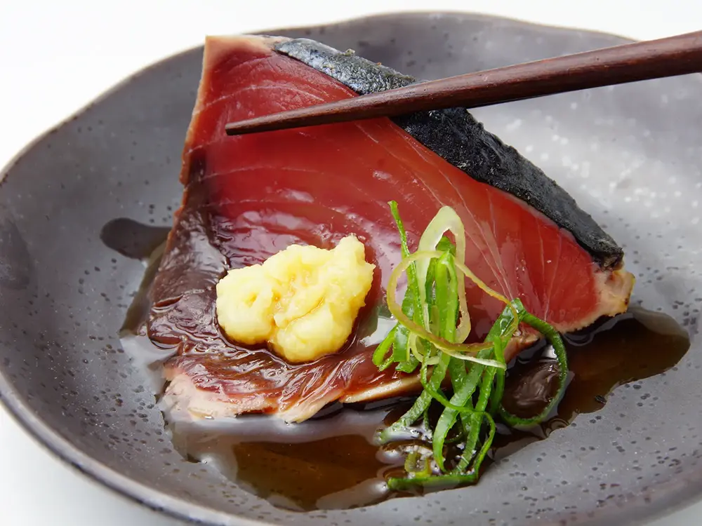 カツオのタタキを薬味と一緒に箸上げした画像