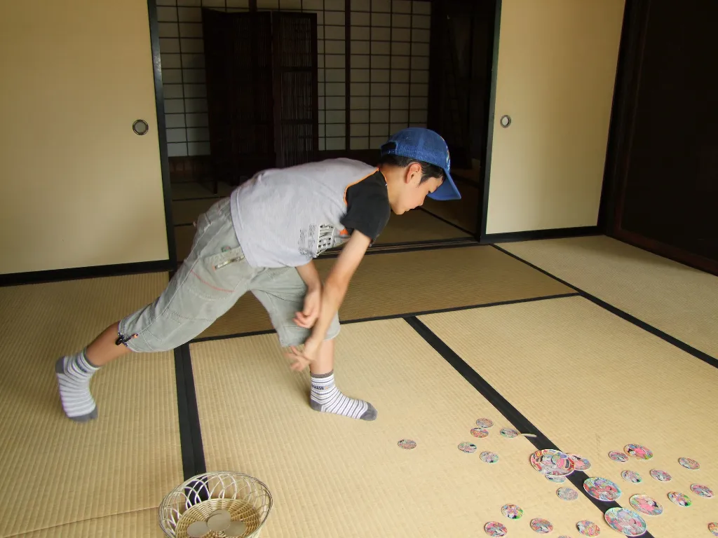  めんこを叩きつけて遊ぶ子どもの画像