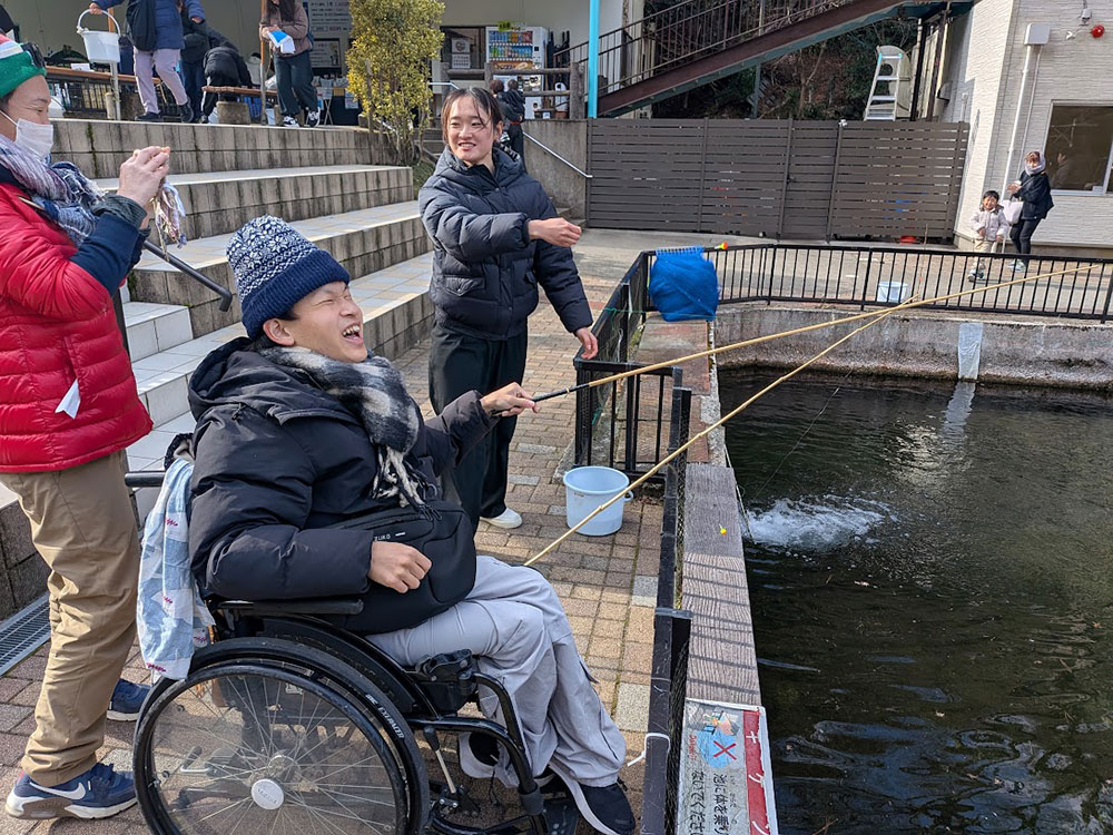 車椅子に乗り、釣り竿を持って笑顔の男性の画像