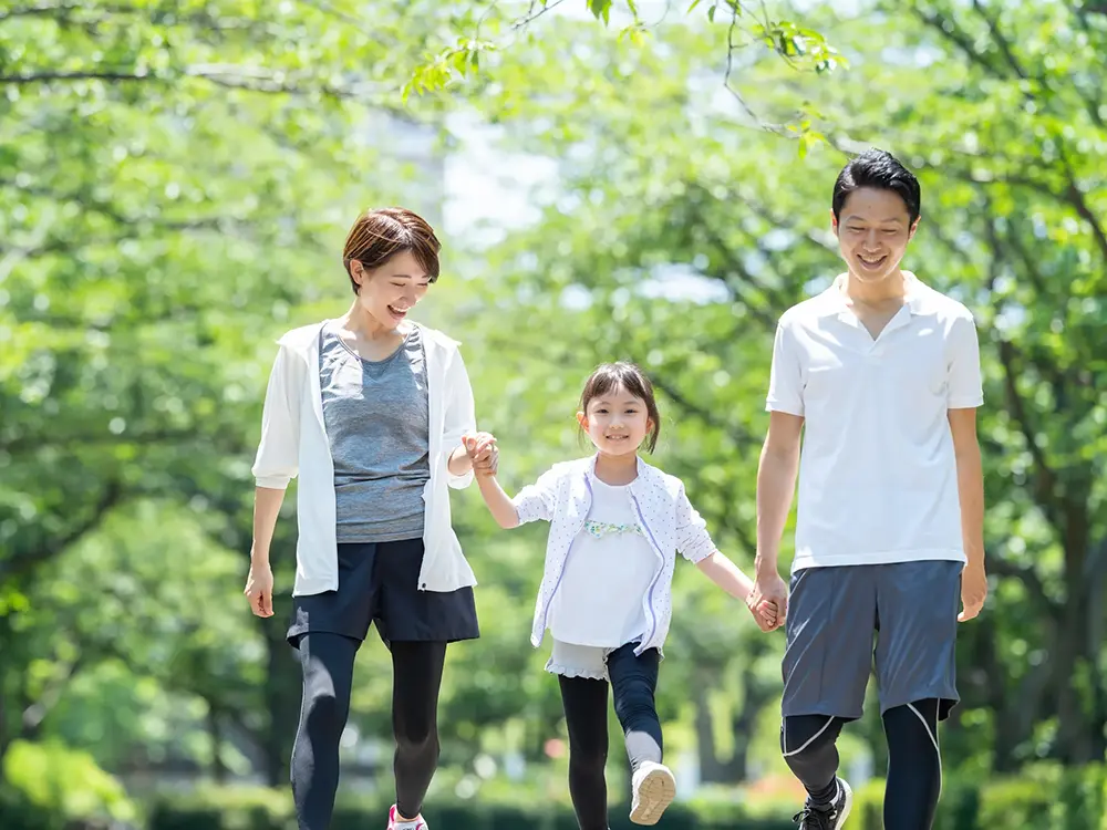 公園で手を繋いで歩く親子3人の画像