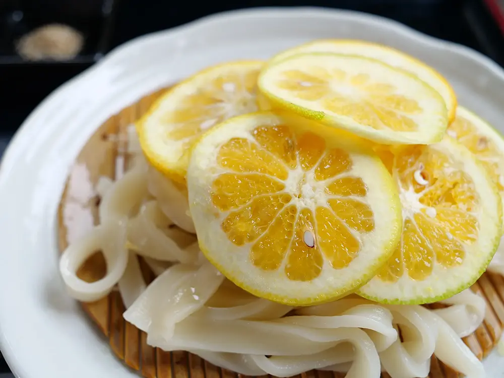 うどんの上に鮮やかなカボスがのった画像