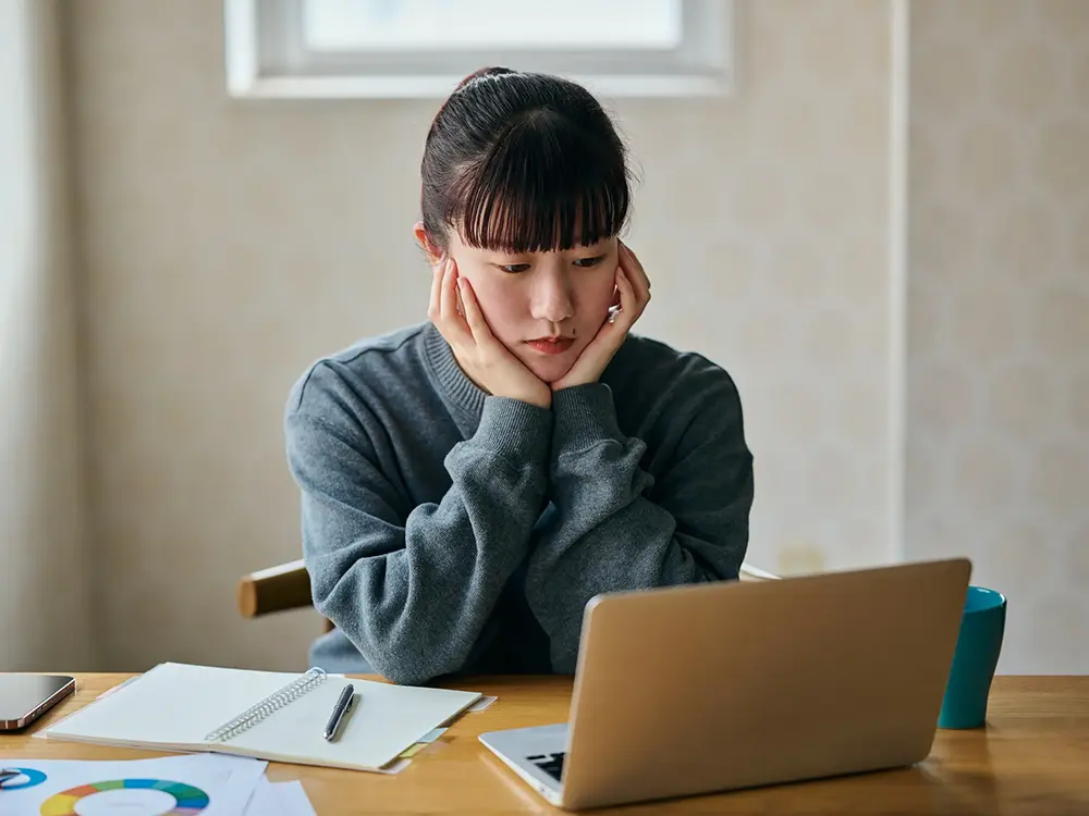 PCを前に考えている女子学生の画像