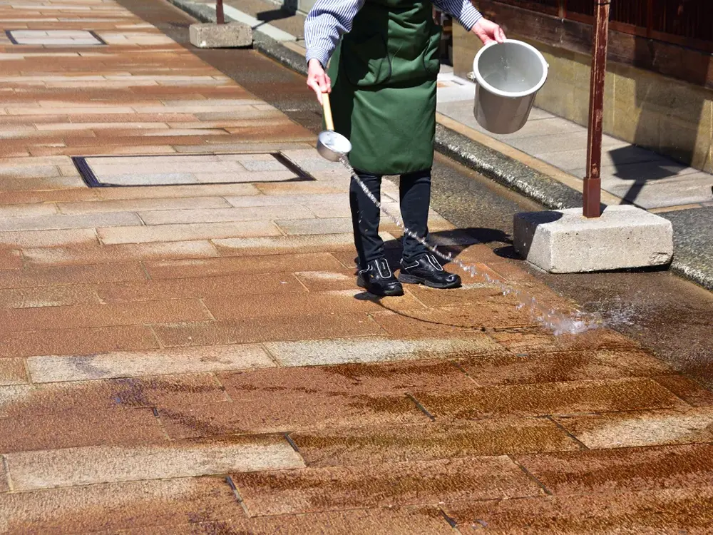 道路に打ち水をしている画像