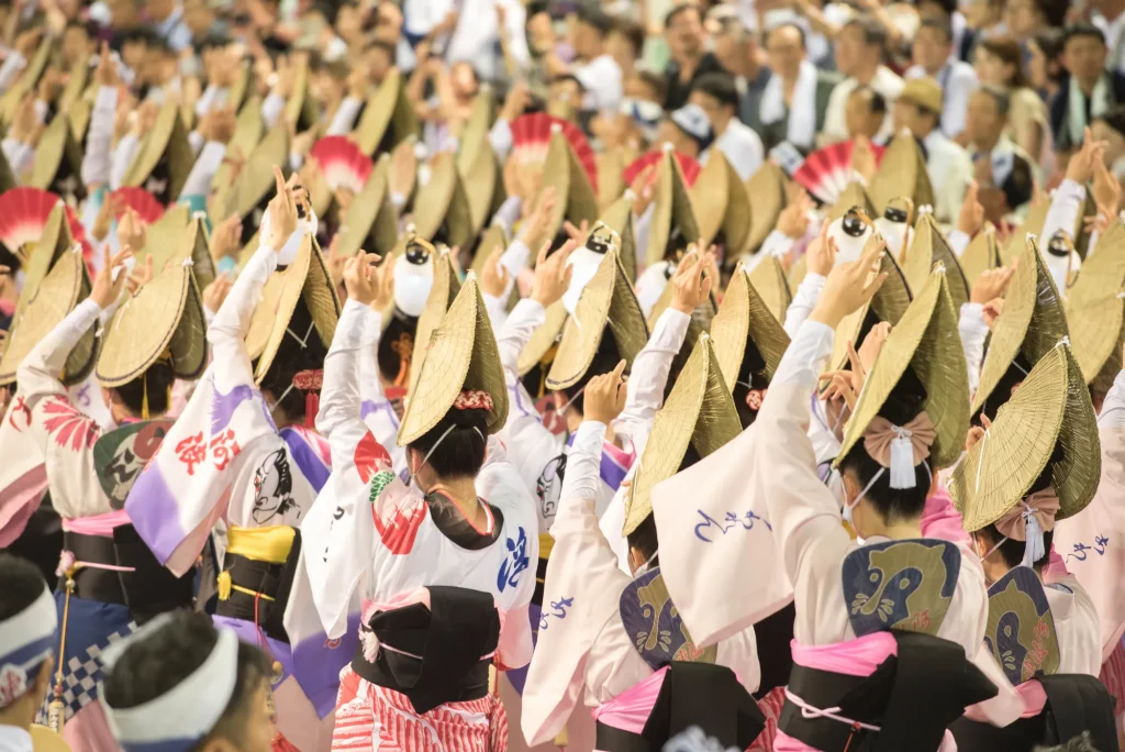 阿波踊りを踊る人と見守る観客の画像
