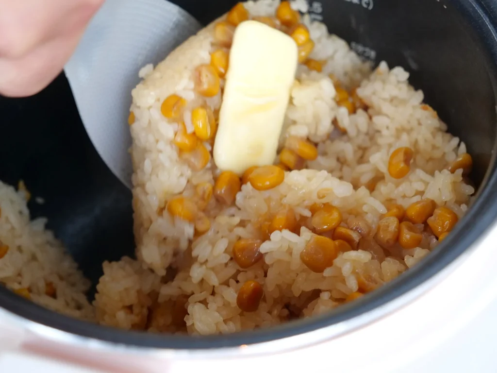 バターを加え、炊飯器の中でご飯を混ぜる様子