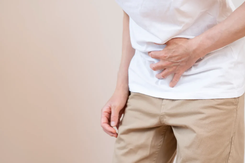 胃腸の不良でお腹を押さえている男性の画像