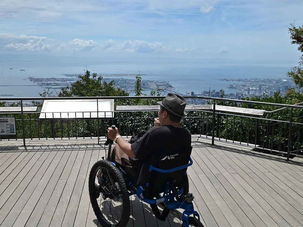 展望台から海を見下ろす車椅子の男性の画像