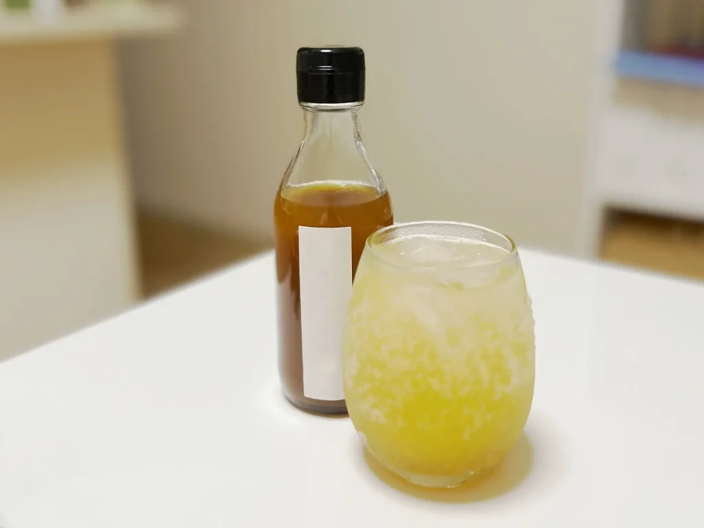 シロップの瓶とグラスに注いだ炭酸で割ったクラフトコーラの画像