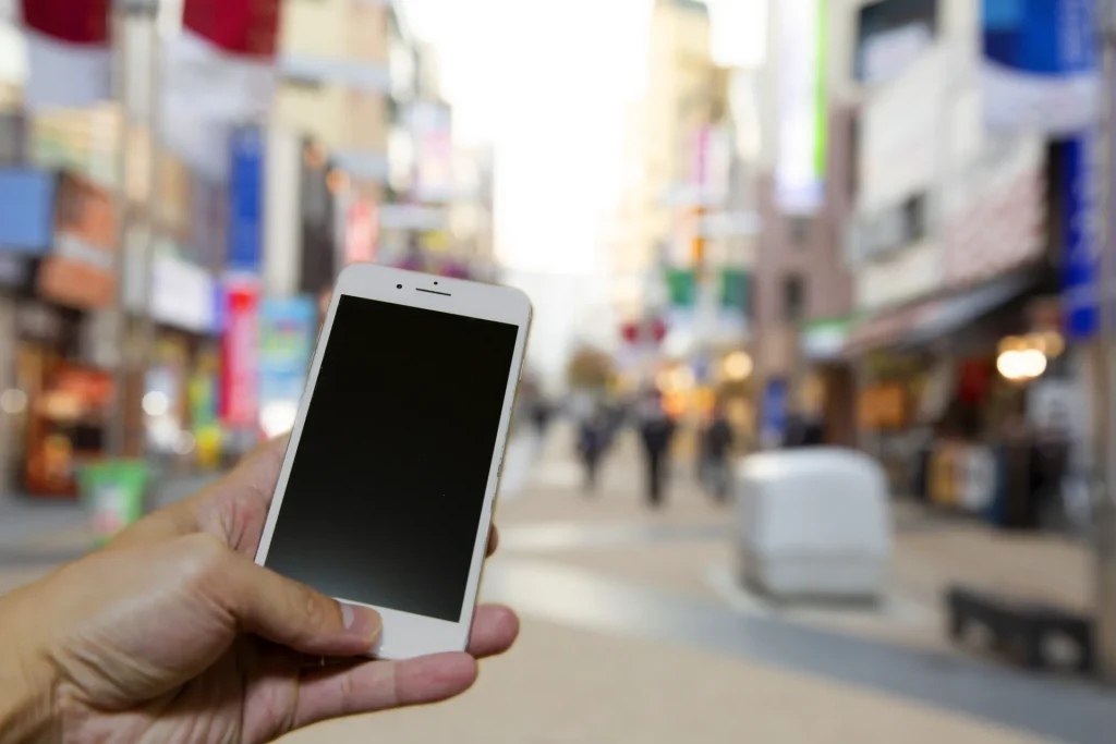 スマートフォンで検索しながら街歩きしている画像